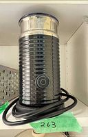 Front view of black ribbed Nespresso grinder on shelf
