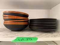 Stack of six bowls and stack of eight plates on shelf