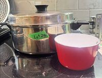 Stainless pot with lid and red enamel pot on stovetop