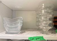 Stack of textured square bowls beside stack of clear footed dessert bowls on shelf