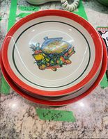 Stacked view showing red rim and centre vegetable graphic of bowls