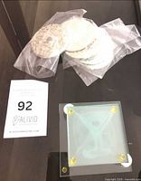 Round silver-plated coasters in bags beside square martini design coaster