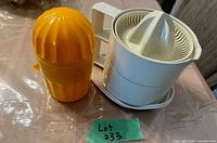 Yellow manual juicer beside white Braun electric juicer