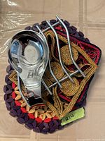 Chrome spoon rest stacked on metal trivet over assorted woven trivets