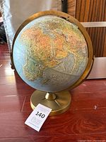 Front view of raised-relief world globe on metal base