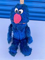 Front view of Ganz Grover plush standing upright next to ruler
