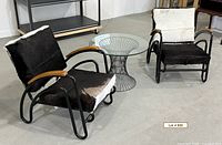 Pair of armchairs beside glass top table, showing overall design and condition