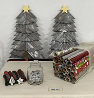 overall lot showing two wooden trees, glass canister with cookie cutters, bin with wrapping paper rolls, folded napkins
