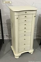 Front view of creamy white jewelry armoire showing nine drawers