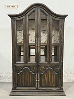 front view of armoire closed showing arched top, wire mesh doors, lower paneled doors