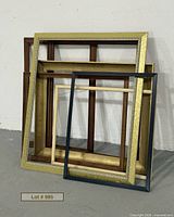 Stack of seven assorted empty frames leaned against wall
