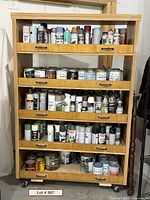full view of wood cabinet on dolly, shelves filled with paint