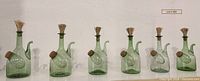 Group view of six matching green glass porrons on shelf