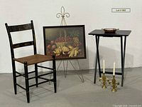 Group view of chair, print on easel, folding table with bowl, candle holders