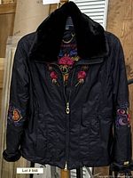 Front view of black Obermeyer ski jacket showing embroidery, zipper and collar