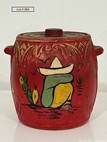Front view showing painted Mexican figure and cactus on red jar