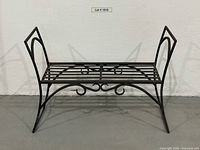 Front view of black wrought iron bench on concrete floor