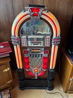 Front view of full-size red and cream jukebox with illuminated arch and control panel