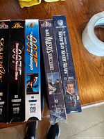 Six vertically standing VHS spines including GoldenEye, Tomorrow Never Dies, Never Say Never Again and others