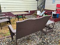 Back view of loveseat bench beside side table and larger glass-top table with chairs
