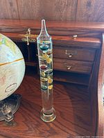 Galileo thermometer in foreground showing colored bulbs and metal tags