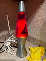 Full view of lava lamp illuminated showing silver base and red wax motion