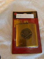 Sealed gold-tone hip flask in retail packaging