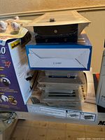 Stacked lot showing boxed items and shrink-wrapped vent grille