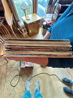 Stack of about 16 vinyl record albums held horizontally showing aged edges
