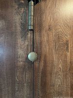 Skeleton wall clock pendulum bob, weight and chains against wood background