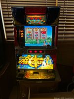 Front view of cabinet powered on showing LCD screen, lit reels and artwork