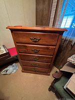 Frontal view of solid wood 5-drawer chest showing brass pulls and overall finish