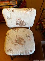 Front view of stool showing worn vinyl seat and back with fruit print