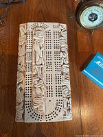 Close-up of carved cribbage board and barometer face
