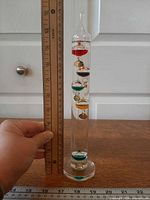 Full view of thermometer beside ruler indicating 11 inch height