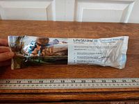 Sealed LifeStraw personal water filter with full package view alongside ruler for scale
