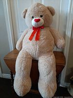 Full front view of large beige teddy bear seated on table