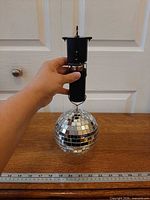 Full kit held by hand beside ruler showing disco ball attached to motor