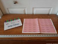 Front and inside of savings tracker booklet displayed on table with ruler for scale