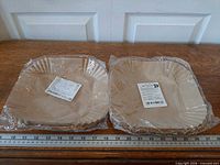 Two shrink-wrapped stacks of square parchment liners beside 24-inch ruler
