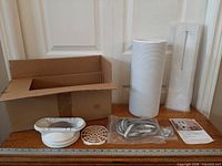 All kit components laid out: box, exhaust hose, sealing plates (packaged), hose adaptor, filter, brush strip, screws