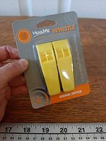 Front of sealed retail package showing two yellow whistles