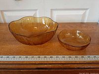 Large and small amber glass bowls side by side with ruler showing scale