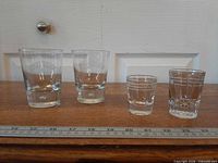 Four glasses lined up: two Baileys tumblers, two Dominion shot glasses with ruler for scale