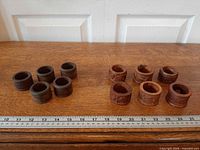 Overview of 13 wooden napkin rings grouped by style next to ruler