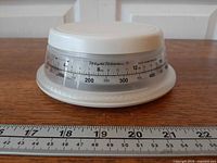 Side view of scale with ruler for size reference showing ounce and gram dial