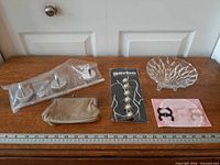 All items laid out: button covers, strap clips, wall hooks package, coin purse, glass dish