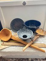 Lot overview showing wooden utensils, enamelware bowl, enamelware funnel and cookbook