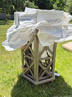 Partially unwrapped wood end table showing lattice design and antique gray finish
