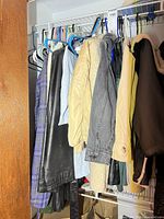 Closet view showing multiple outerwear pieces on hangers including plaid coat, faux leather coat, quilted jacket, denim sherpa jacket and others